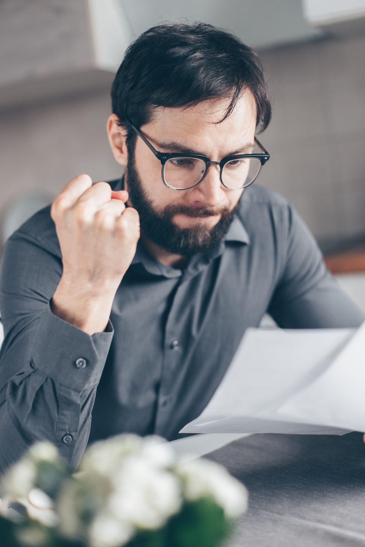 A man closely reading through a stack of paperwork at a desk