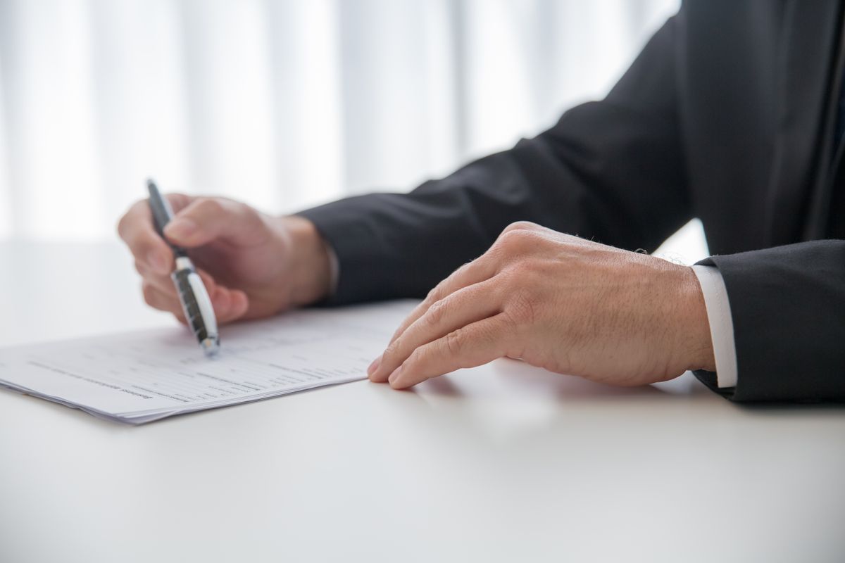 A businessman carefully signing important documents at an office desk